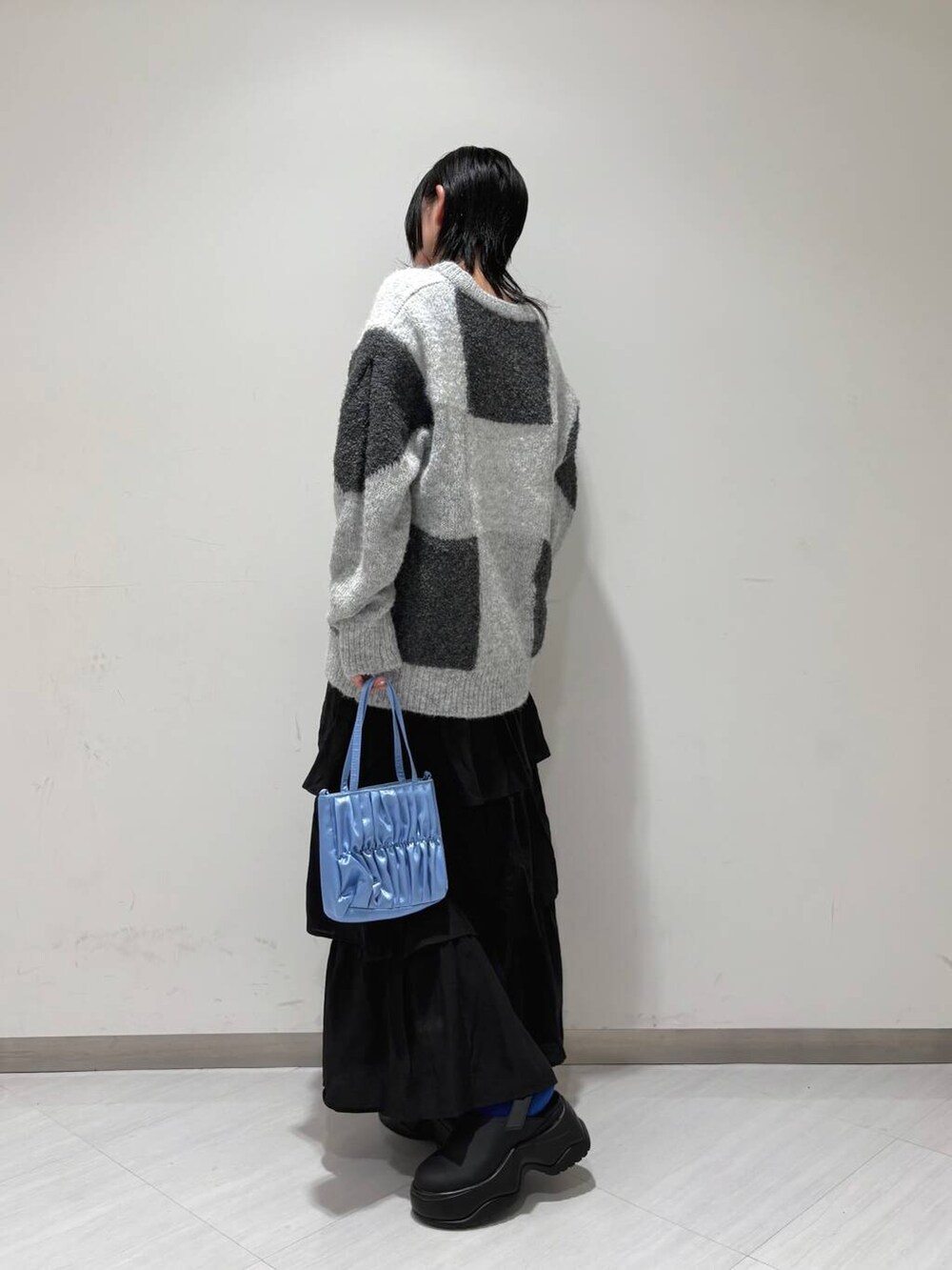 ブラック系のスカート、グレー系のニット/セーター、ブラック系のサンダルを着用したレディースの冬コーディネートの2枚目の写真