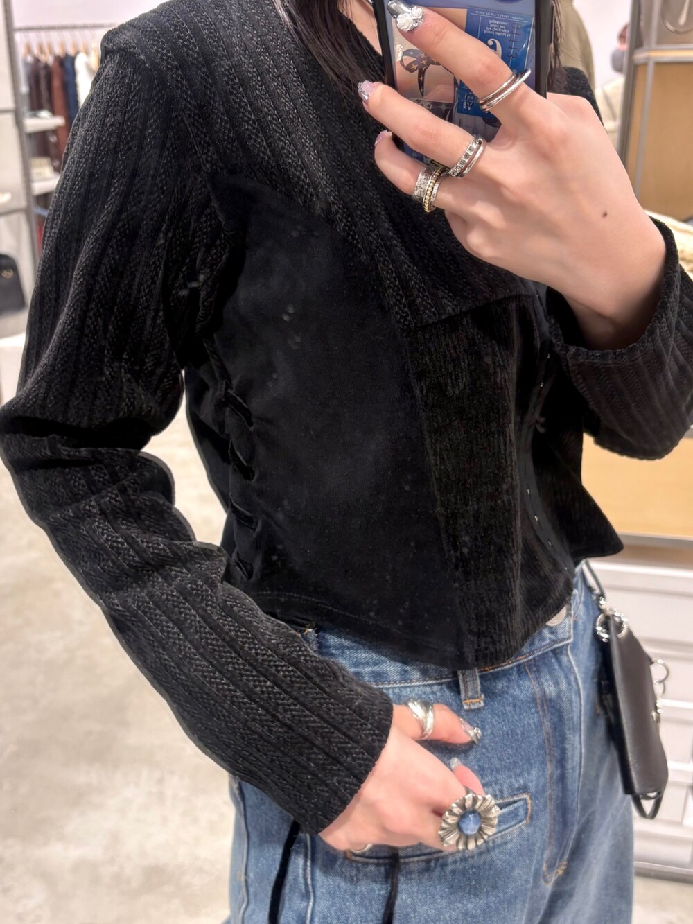 ブラック系のカーディガン/ボレロ、ブラック系のショルダーバッグ、ブルー系のデニムパンツを着用したレディースの冬コーディネートの3枚目の写真