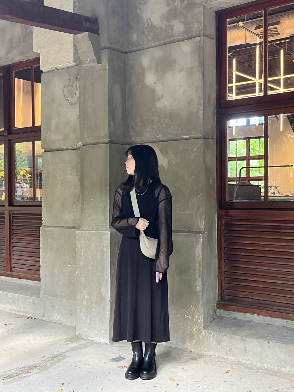 ブラック系のジャンパースカート、グレー系のボディバッグ/ウエストポーチ、ブラック系のブーツを着用したレディースの春コーディネートの2枚目の写真