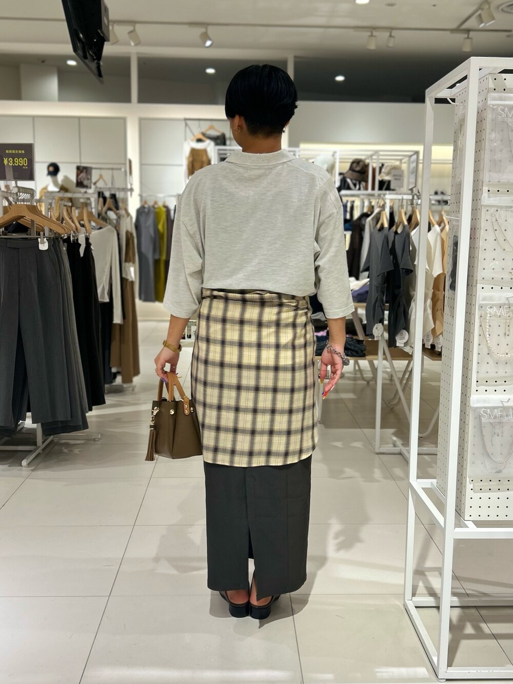 グレー系のスカート、ベージュ系のポロシャツ、ベージュ系のシャツ/ブラウスを着用したレディースの秋コーディネートの3枚目の写真