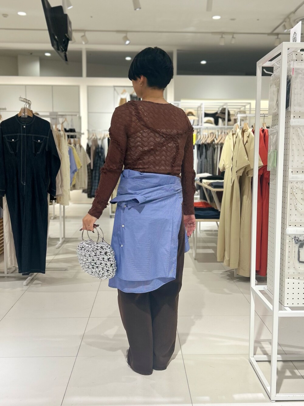 ブラウン系のデニムパンツ、シルバー系のハンドバッグ、シルバー系のその他シューズを着用したレディースの夏コーディネートの3枚目の写真