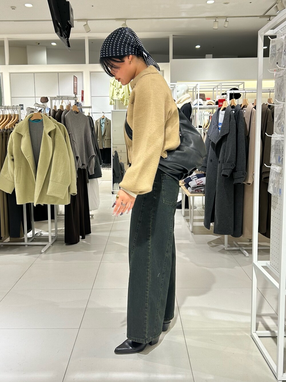 ホワイト系のニット/セーター、ベージュ系のカーディガン/ボレロ、ブラック系のショルダーバッグを着用したレディースの冬コーディネートの3枚目の写真