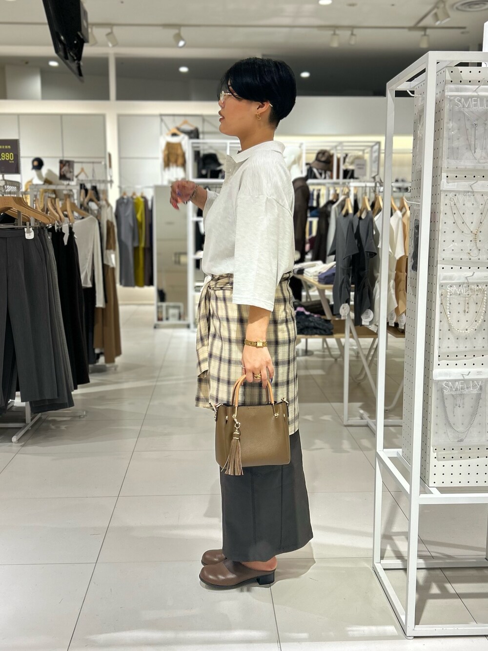 グレー系のスカート、ベージュ系のポロシャツ、ベージュ系のシャツ/ブラウスを着用したレディースの秋コーディネートの2枚目の写真