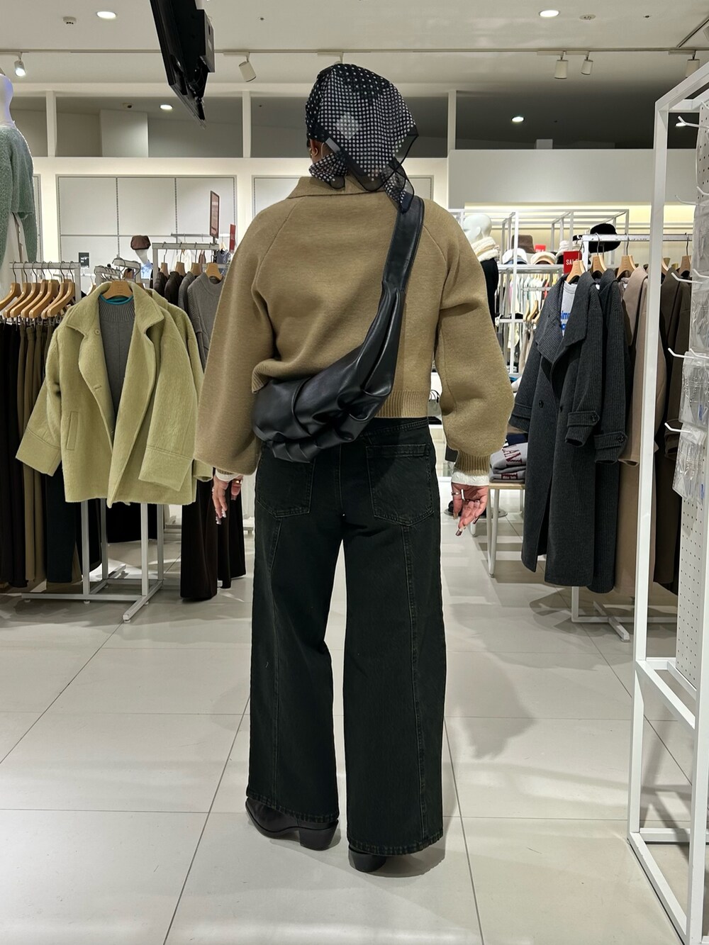 ホワイト系のニット/セーター、ベージュ系のカーディガン/ボレロ、ブラック系のショルダーバッグを着用したレディースの冬コーディネートの4枚目の写真