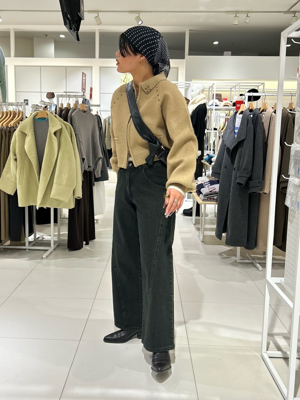 ホワイト系のニット/セーター、ベージュ系のカーディガン/ボレロ、ブラック系のショルダーバッグを着用したレディースの冬コーディネートの2枚目の写真