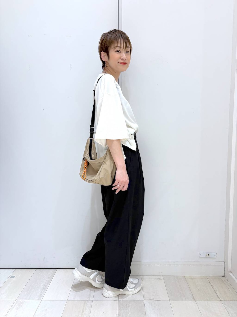 ブラック系のその他パンツ、ベージュ系のTシャツ/カットソー、ホワイト系のスニーカーを着用したレディースの春コーディネートの2枚目の写真