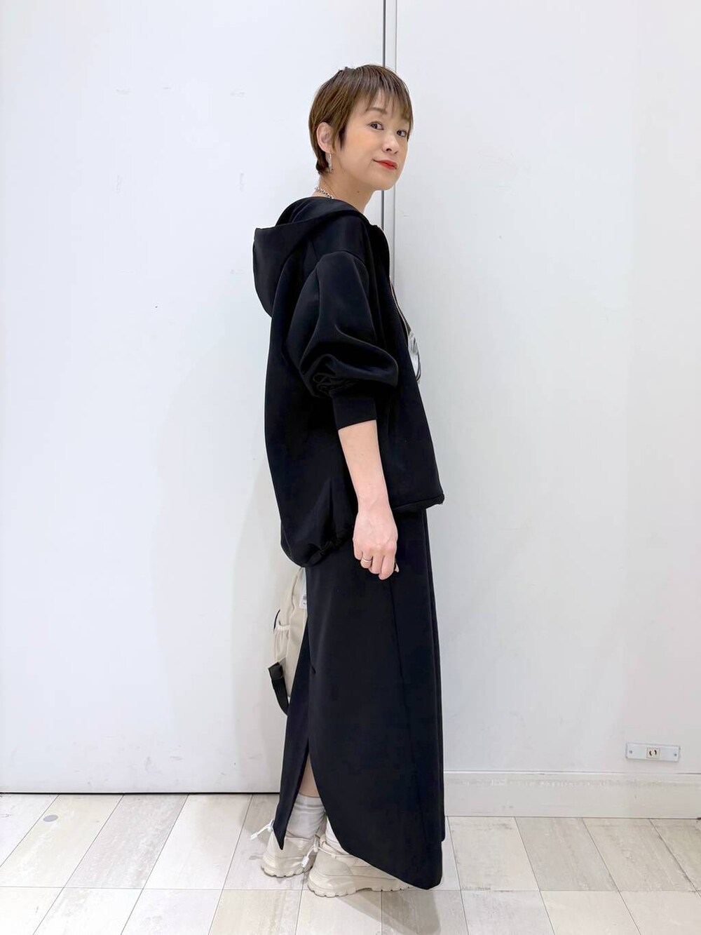 ホワイト系のバックパック/リュック、ブラック系のスカート、ブラック系のパーカーを着用したレディースの春コーディネートの2枚目の写真