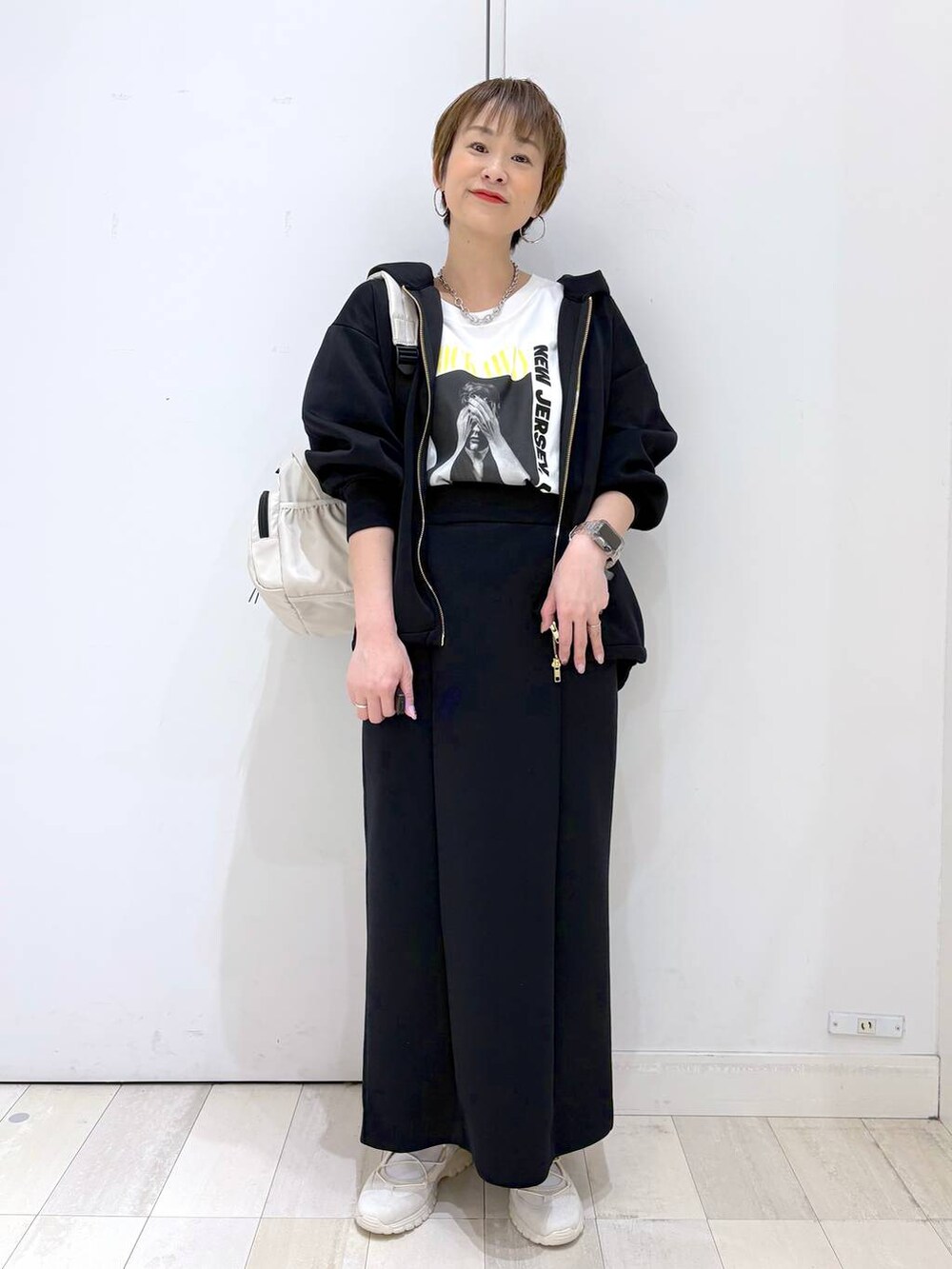 ホワイト系のバックパック/リュック、ブラック系のスカート、ブラック系のパーカーを着用したレディースの春コーディネートの3枚目の写真