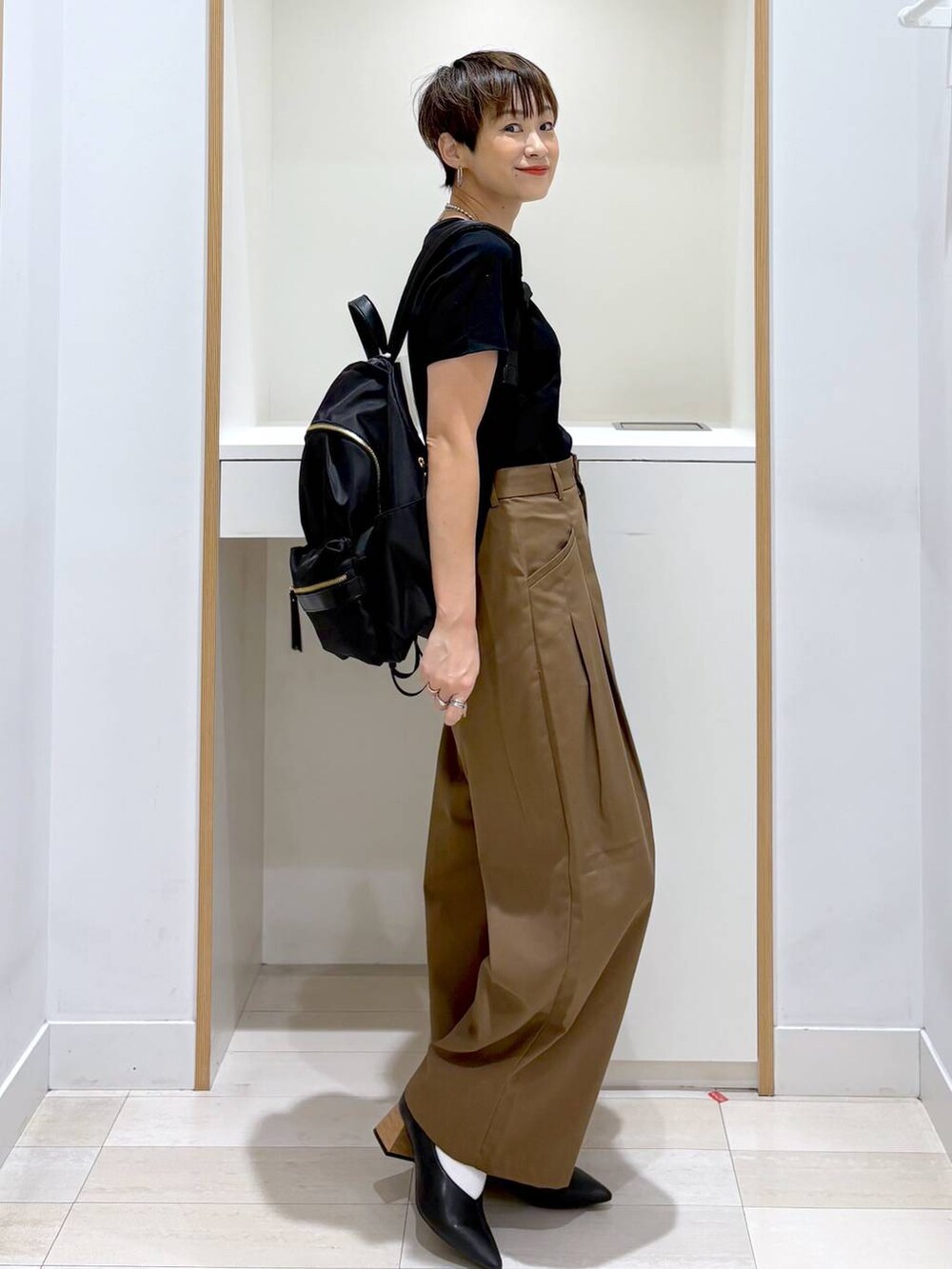 ブラック系のバックパック/リュック、ブラック系のTシャツ/カットソー、ブラック系のパンプスを着用したレディースの夏コーディネートの6枚目の写真