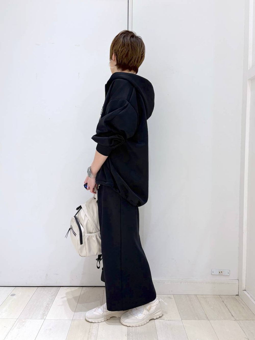 ホワイト系のバックパック/リュック、ブラック系のスカート、ブラック系のパーカーを着用したレディースの春コーディネートの5枚目の写真