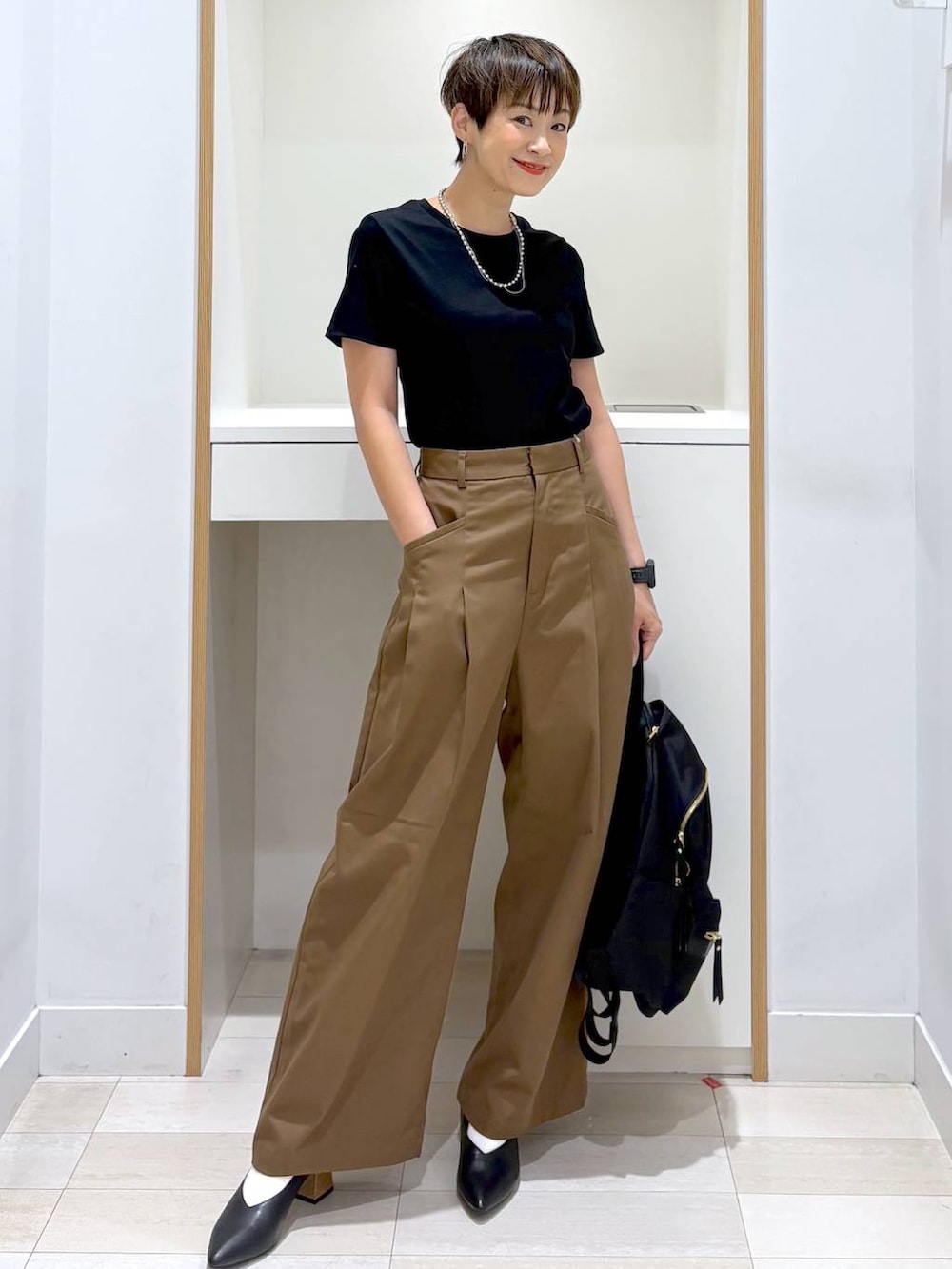 ブラック系のバックパック/リュック、ブラック系のTシャツ/カットソー、ブラック系のパンプスを着用したレディースの夏コーディネートの3枚目の写真