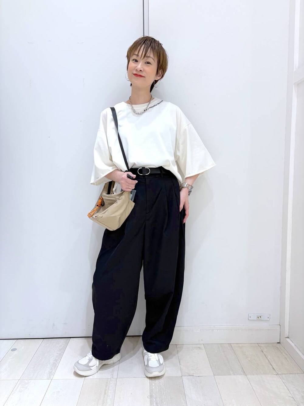ブラック系のその他パンツ、ベージュ系のTシャツ/カットソー、ホワイト系のスニーカーを着用したレディースの春コーディネートの4枚目の写真