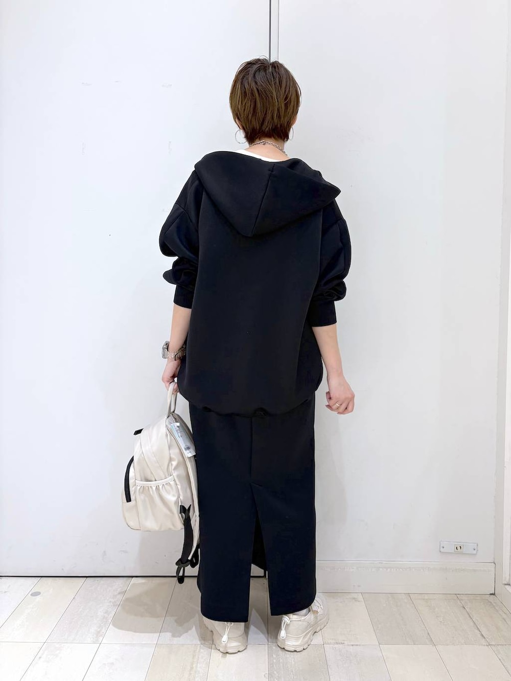 ホワイト系のバックパック/リュック、ブラック系のスカート、ブラック系のパーカーを着用したレディースの春コーディネートの4枚目の写真