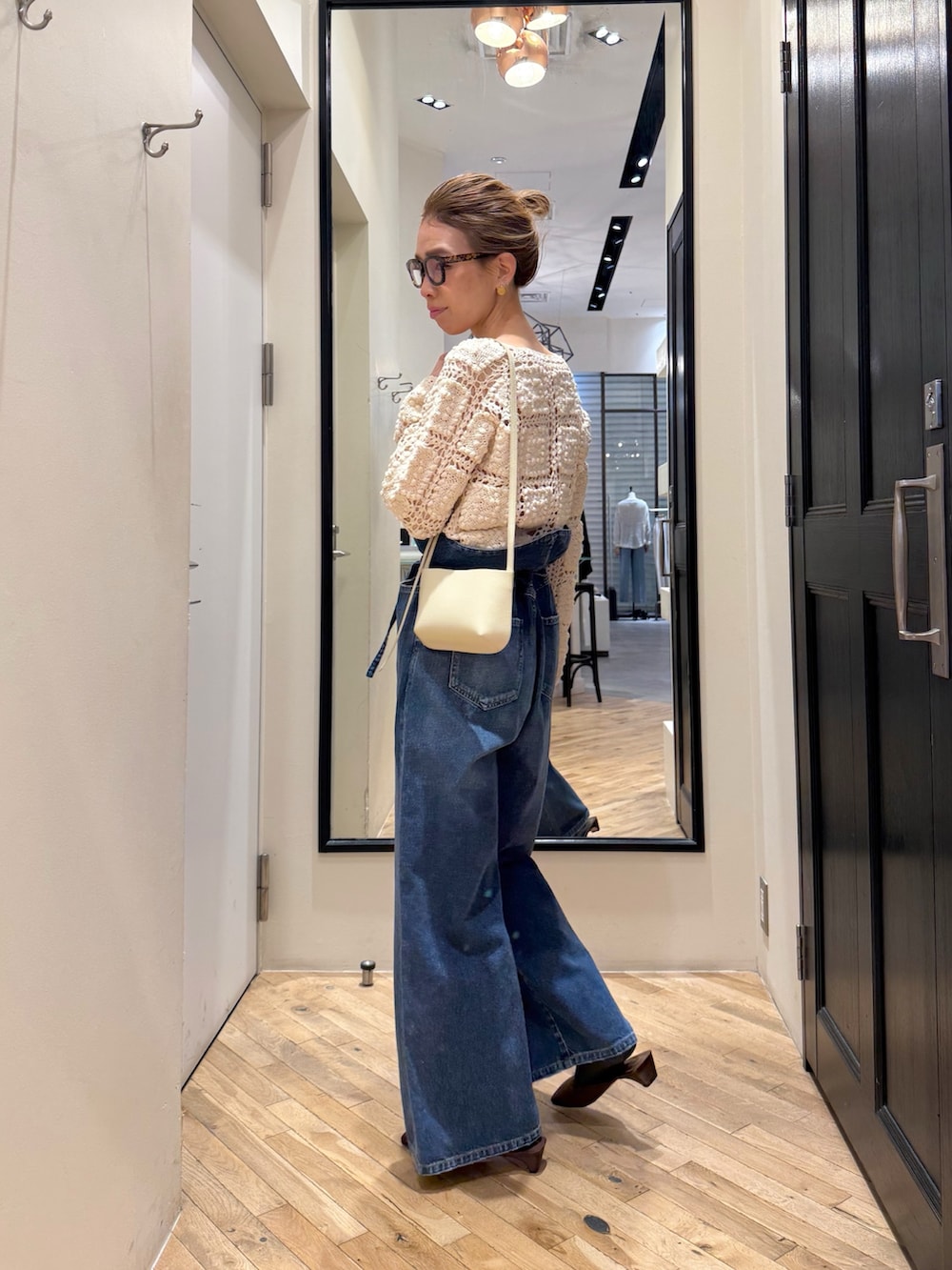 ブルー系のデニムパンツ、ホワイト系のカーディガン/ボレロ、ブラウン系のサンダルを着用したレディースの冬コーディネートの5枚目の写真