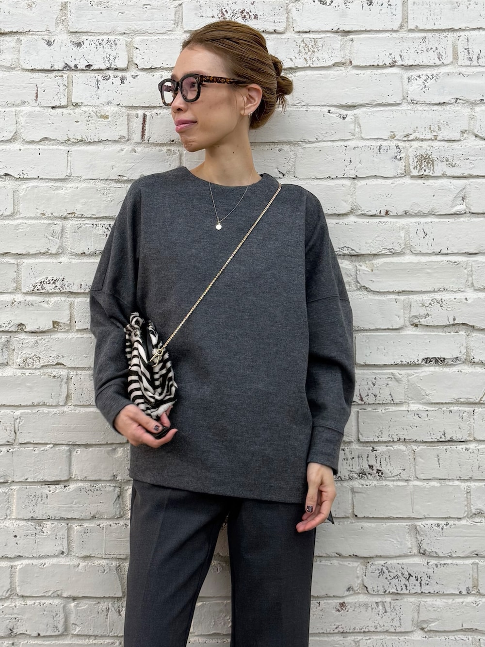 ブラック系のクラッチバッグ、グレー系のTシャツ/カットソー、グレー系のその他パンツを着用したレディースの秋コーディネートの7枚目の写真