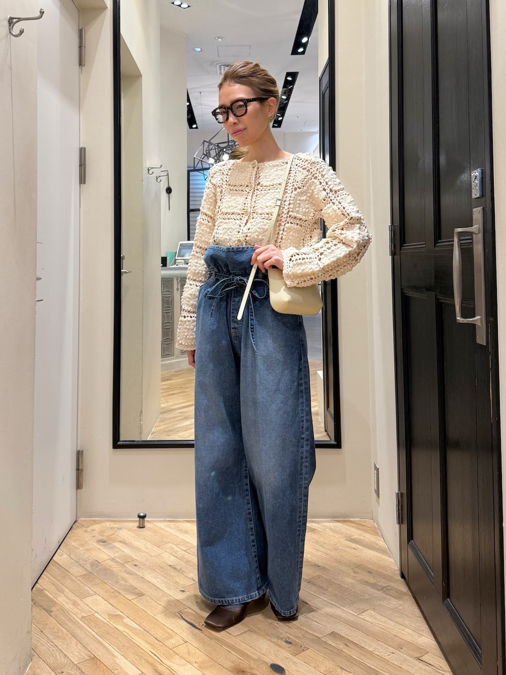 ブルー系のデニムパンツ、ホワイト系のカーディガン/ボレロ、ブラウン系のサンダルを着用したレディースの冬コーディネートの2枚目の写真