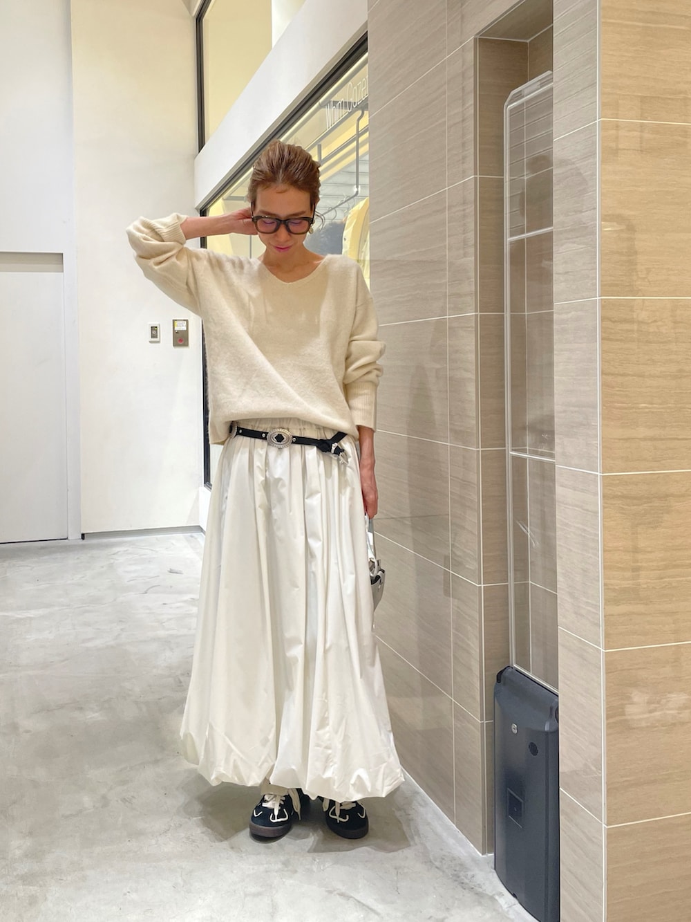ホワイト系のスカート、ホワイト系のニット/セーター、ブラック系のベルトを着用したレディースの秋コーディネートの4枚目の写真