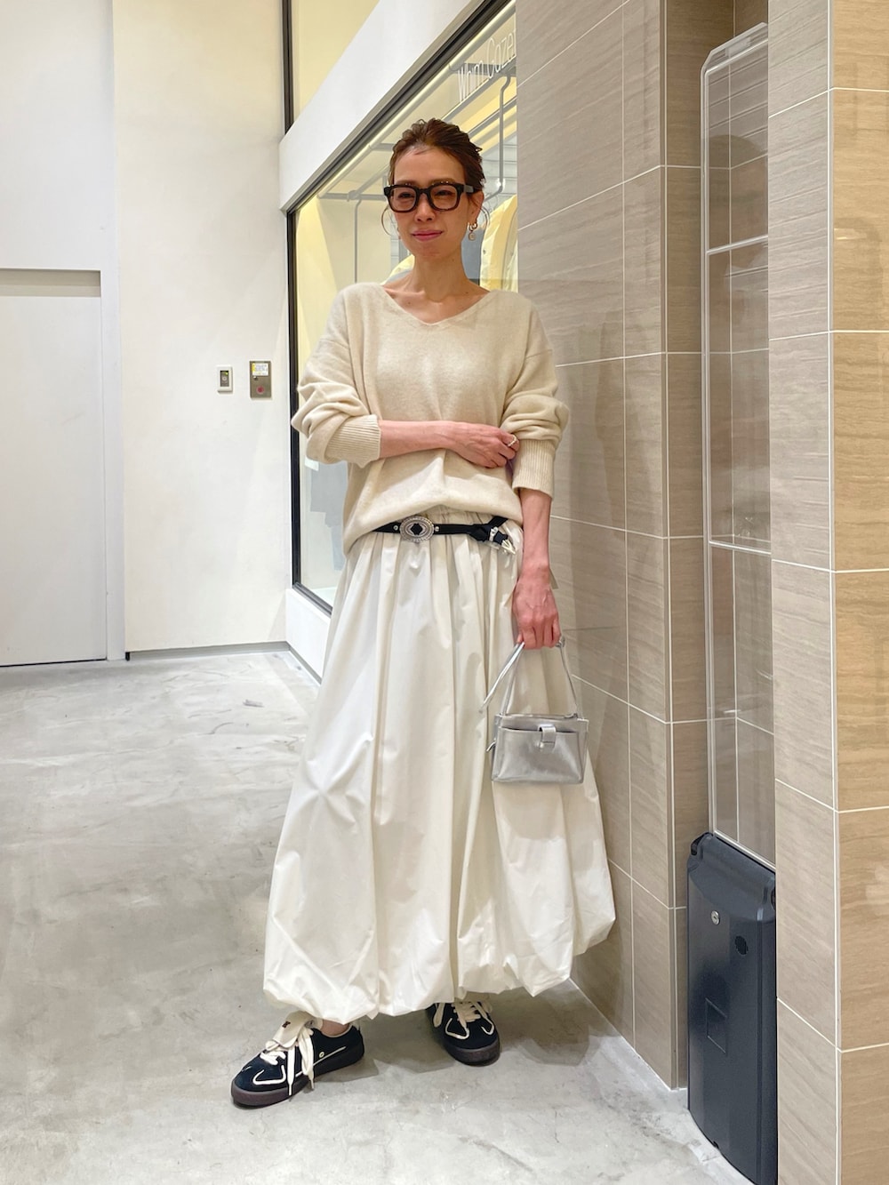 ホワイト系のスカート、ホワイト系のニット/セーター、ブラック系のベルトを着用したレディースの秋コーディネートの6枚目の写真