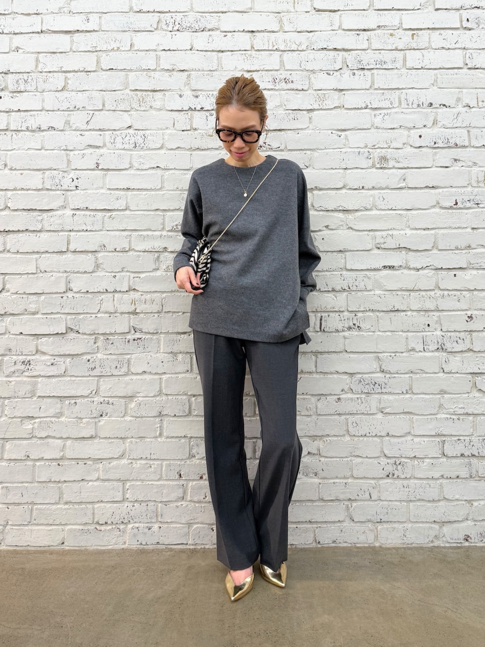 ブラック系のクラッチバッグ、グレー系のTシャツ/カットソー、グレー系のその他パンツを着用したレディースの秋コーディネートの4枚目の写真