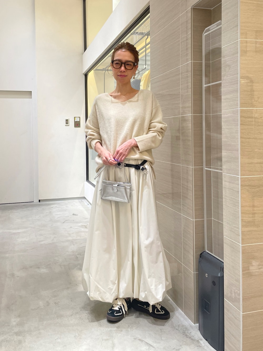 ホワイト系のスカート、ホワイト系のニット/セーター、ブラック系のベルトを着用したレディースの秋コーディネートの2枚目の写真