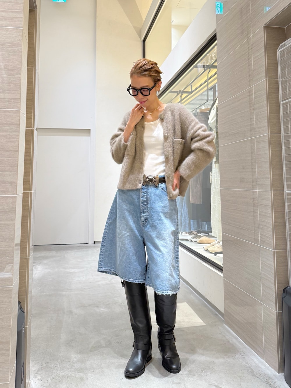 ブルー系のデニムパンツ、ベージュ系のカーディガン/ボレロ、シルバー系のネックレスを着用したレディースの夏コーディネートの2枚目の写真