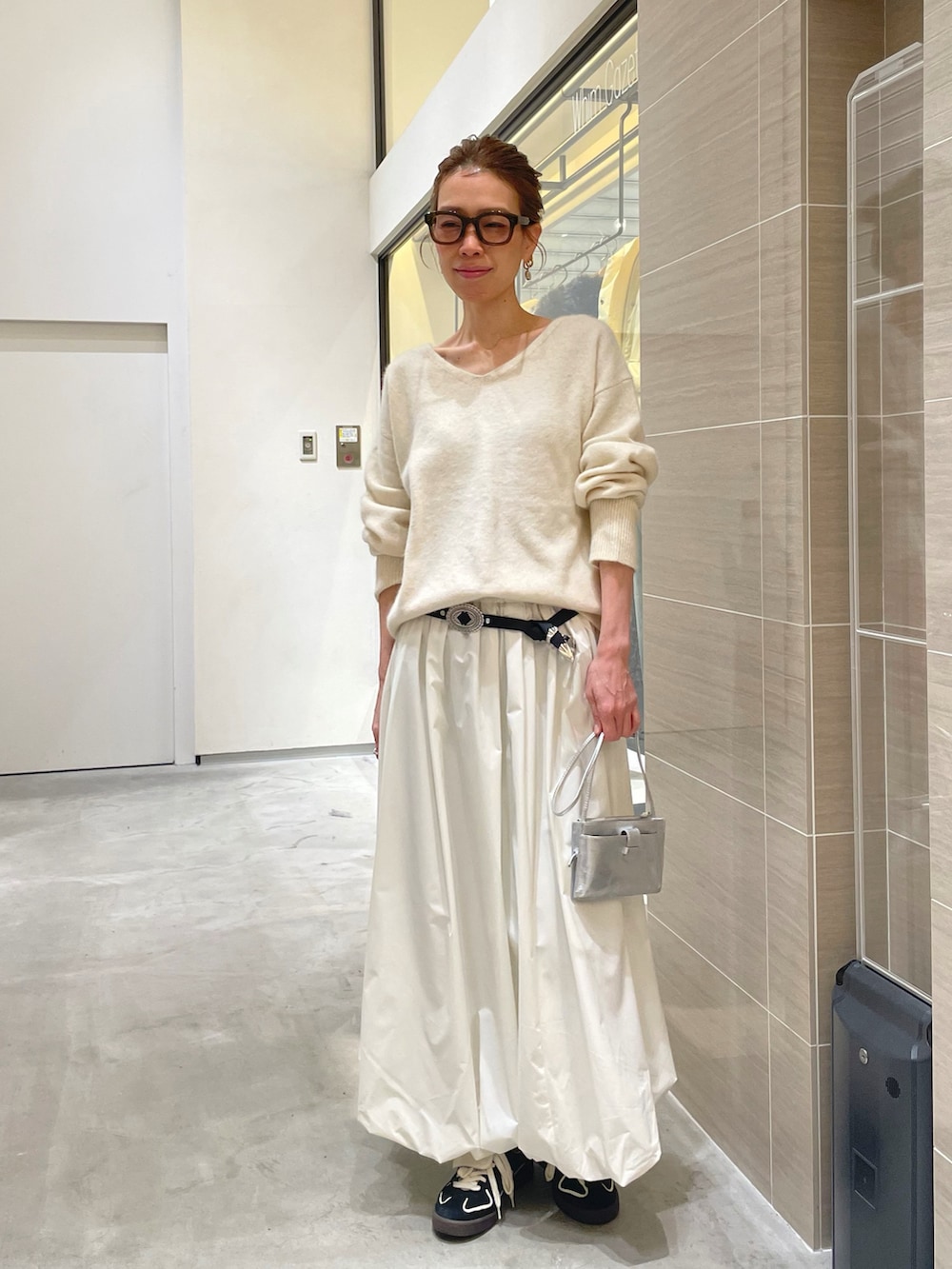 ホワイト系のスカート、ホワイト系のニット/セーター、ブラック系のベルトを着用したレディースの秋コーディネートの5枚目の写真