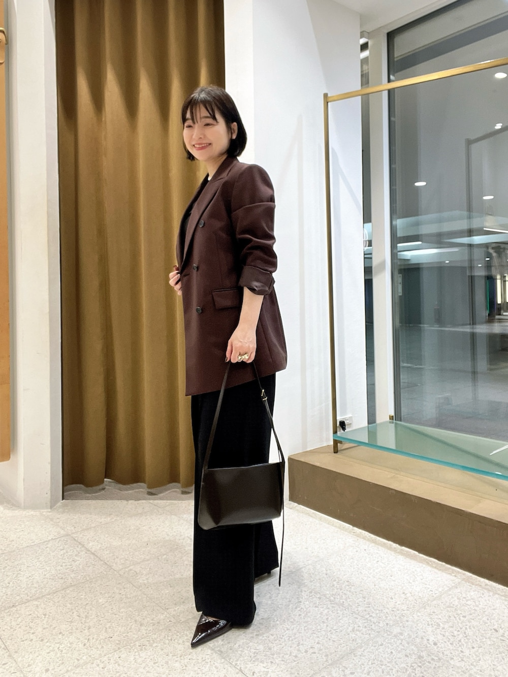ブラウン系のテーラードジャケット、ブラウン系のショルダーバッグ、ブラウン系のパンプスを着用したレディースの秋コーディネートの2枚目の写真