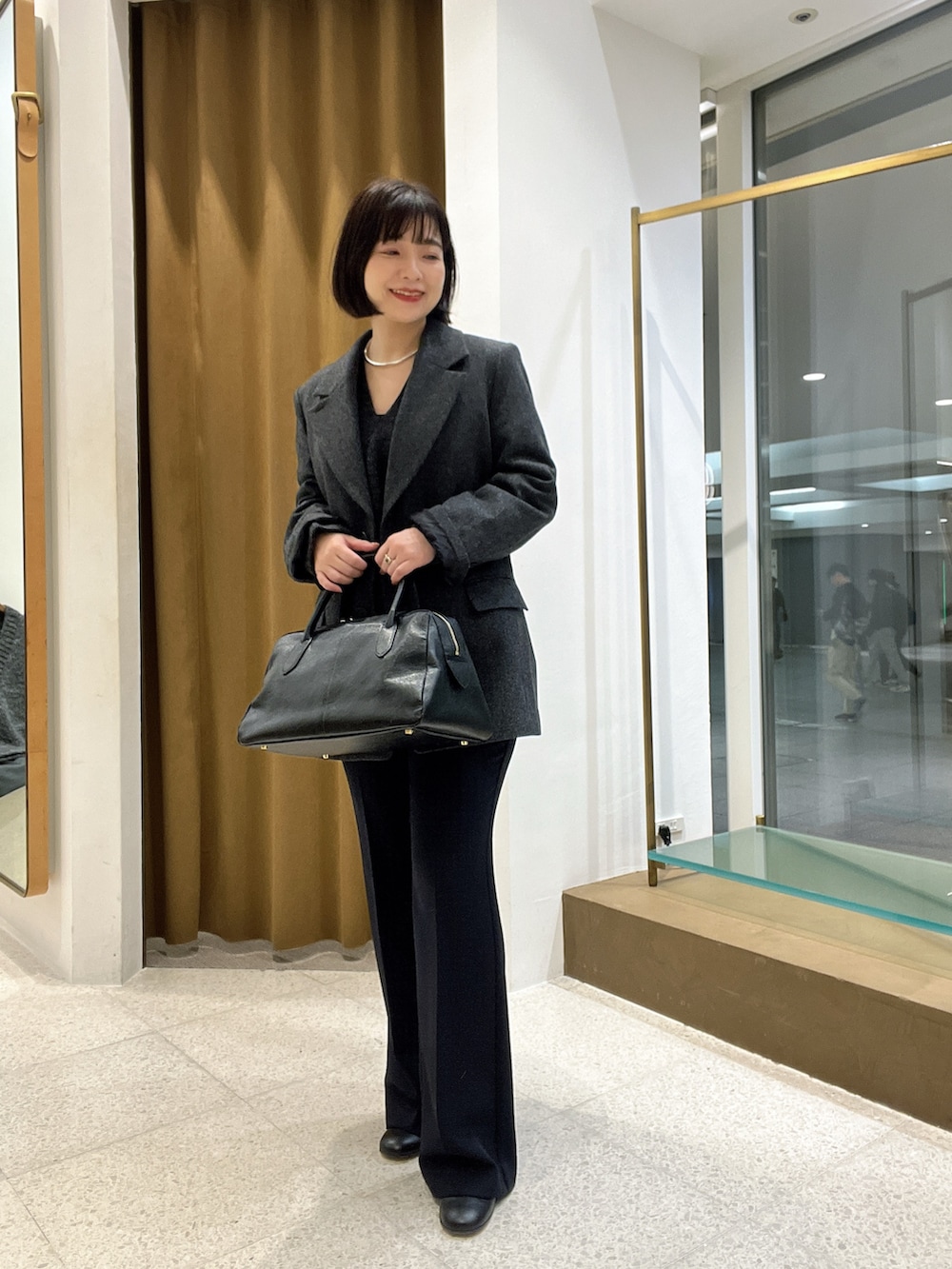 グレー系のテーラードジャケット、グレー系のニット/セーター、ブラック系のトートバッグを着用したレディースの秋コーディネートの4枚目の写真