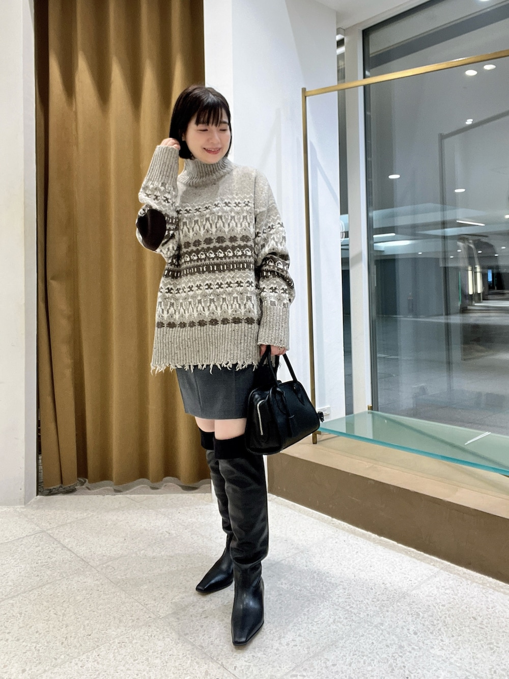 ベージュ系のニット/セーター、グレー系のスカート、ブラック系のボストンバッグを着用したレディースの秋コーディネートの2枚目の写真