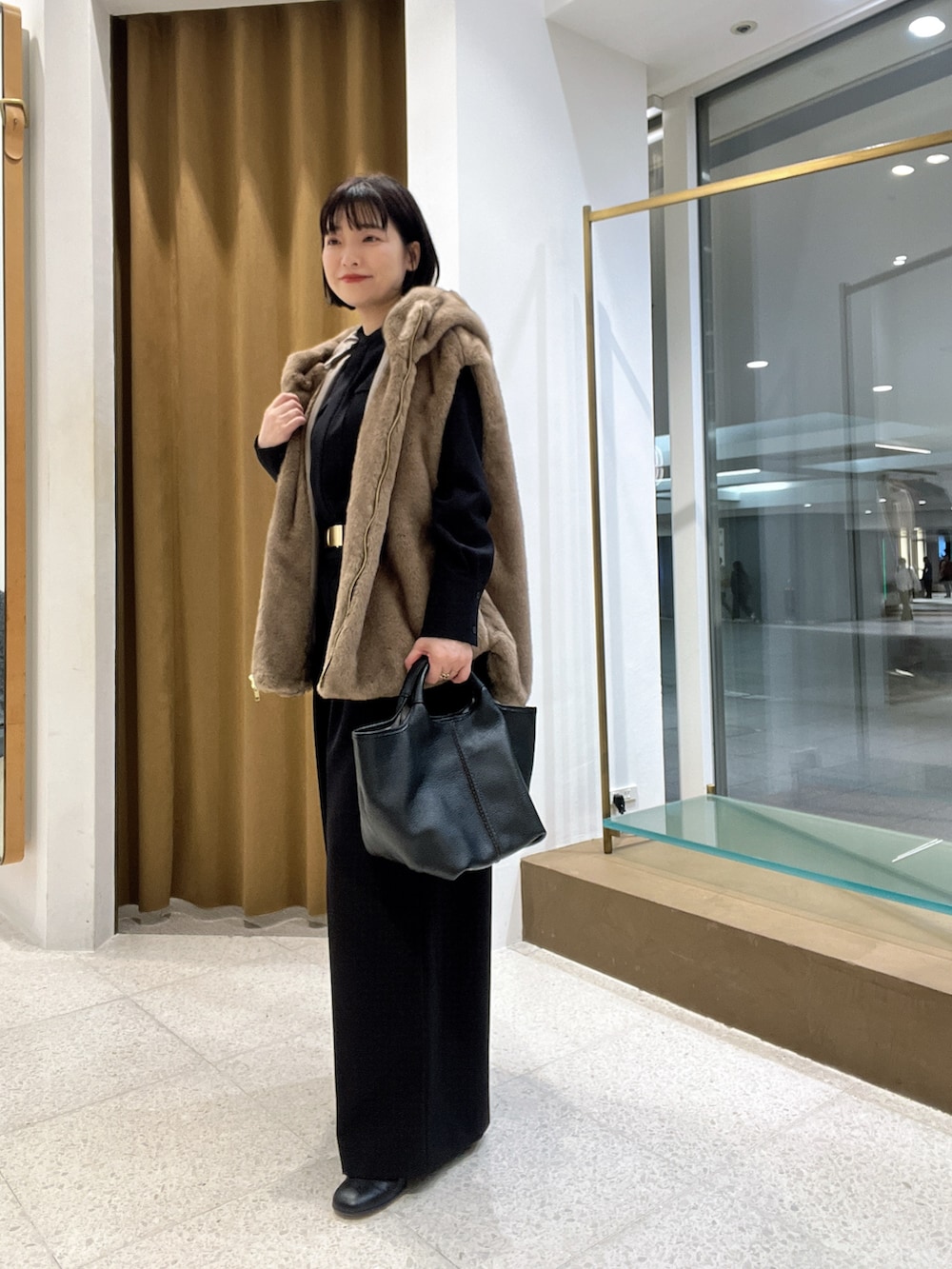 ブラウン系のその他アウター、ブラック系のつなぎ/オールインワン、ブラック系のトートバッグを着用したレディースの秋コーディネートの2枚目の写真