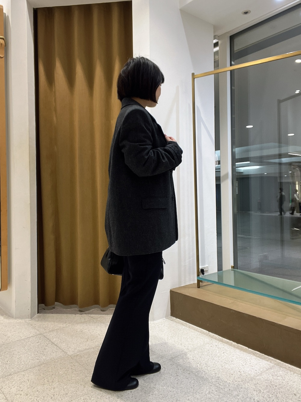 グレー系のテーラードジャケット、グレー系のニット/セーター、ブラック系のトートバッグを着用したレディースの秋コーディネートの3枚目の写真