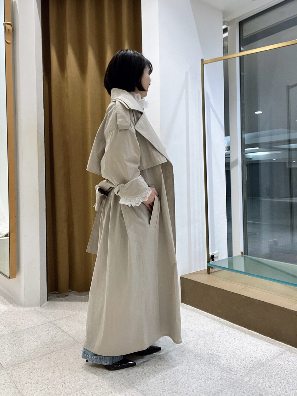 ベージュ系のトレンチコート、ブルー系のデニムパンツ、ホワイト系のシャツ/ブラウスを着用したレディースの秋コーディネートの3枚目の写真