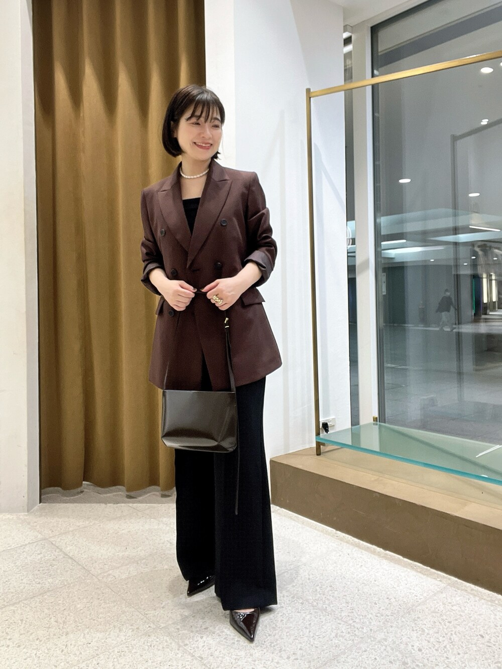 ブラウン系のテーラードジャケット、ブラウン系のショルダーバッグ、ブラウン系のパンプスを着用したレディースの秋コーディネートの4枚目の写真