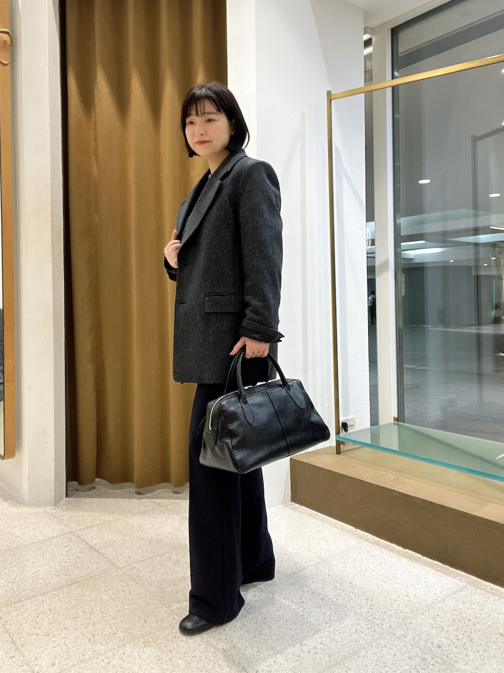 グレー系のテーラードジャケット、グレー系のニット/セーター、ブラック系のトートバッグを着用したレディースの秋コーディネートの2枚目の写真