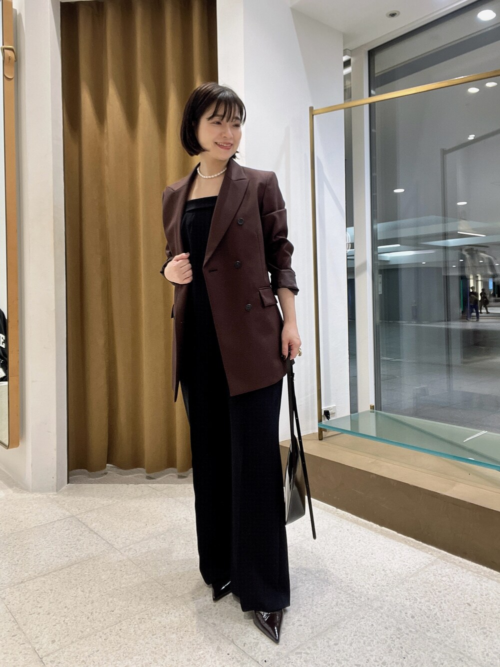 ブラウン系のテーラードジャケット、ブラウン系のショルダーバッグ、ブラウン系のパンプスを着用したレディースの秋コーディネートの5枚目の写真