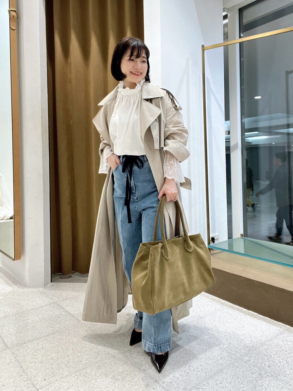 ベージュ系のトレンチコート、ブルー系のデニムパンツ、ホワイト系のシャツ/ブラウスを着用したレディースの秋コーディネートの5枚目の写真