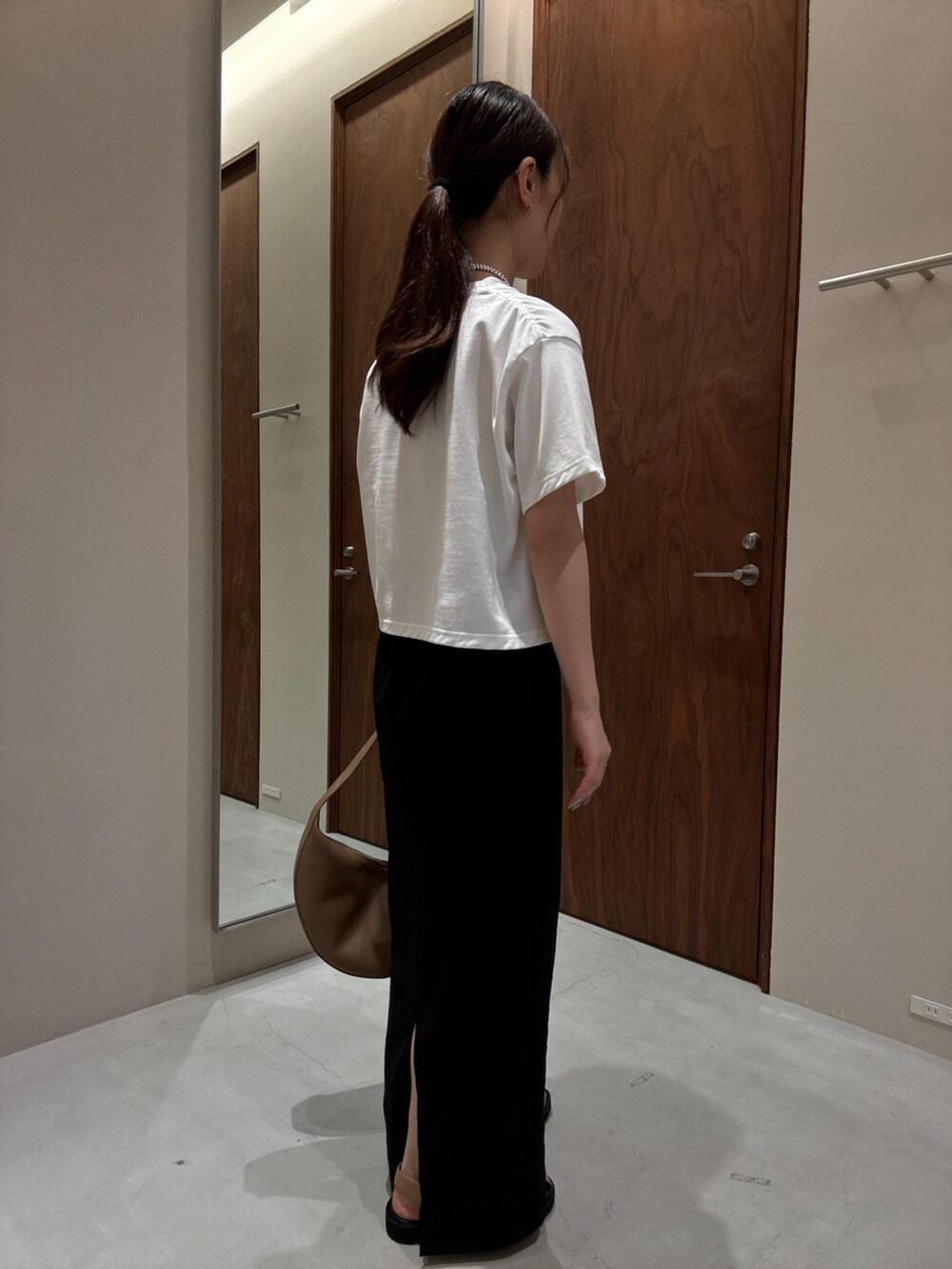 ホワイト系のTシャツ/カットソー、ブラック系のスカート、ベージュ系のサンダルを着用したレディースの夏コーディネートの3枚目の写真