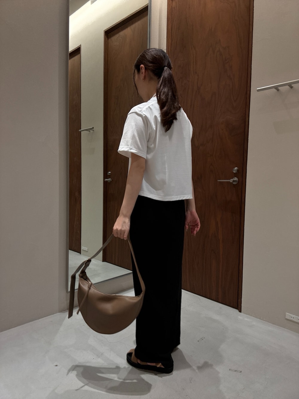 ホワイト系のTシャツ/カットソー、ブラック系のスカート、ベージュ系のサンダルを着用したレディースの夏コーディネートの2枚目の写真