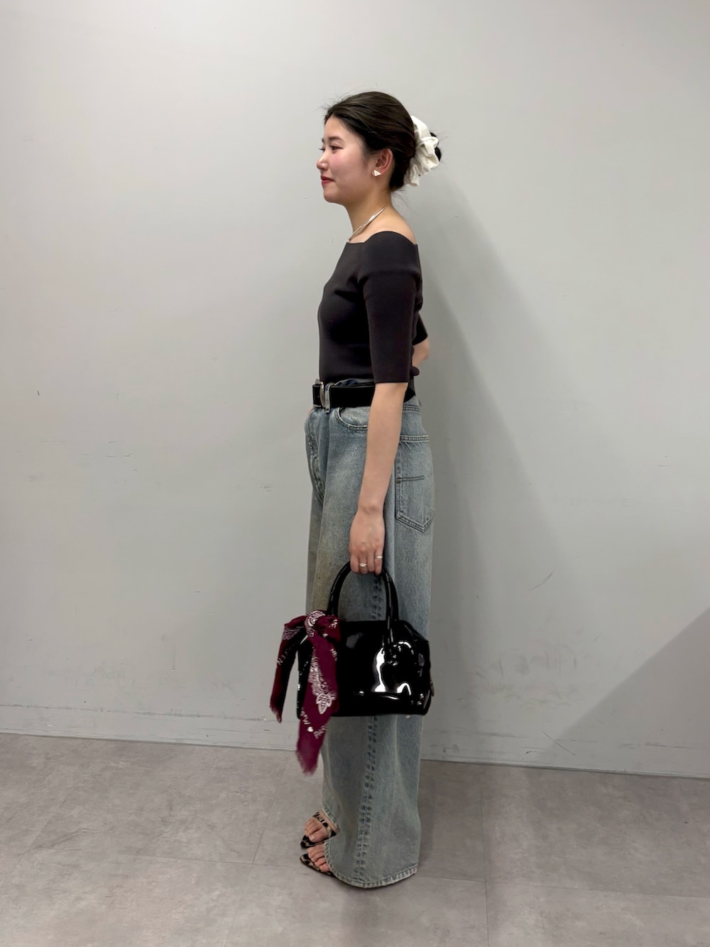 ブルー系のデニムパンツ、ブラック系のボストンバッグ、イエロー系のサンダルを着用したレディースの春コーディネートの2枚目の写真