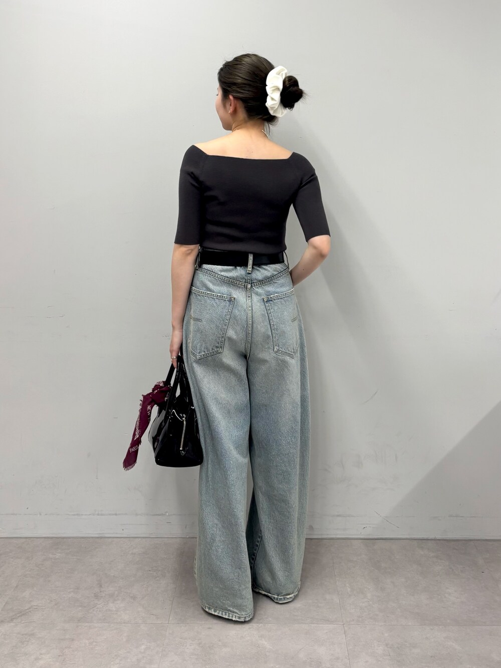 ブルー系のデニムパンツ、ブラック系のボストンバッグ、イエロー系のサンダルを着用したレディースの春コーディネートの3枚目の写真