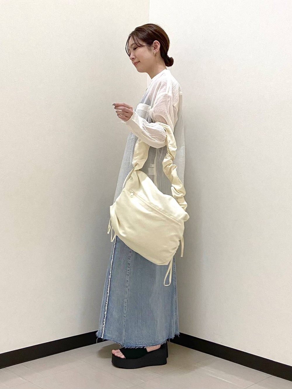 ブラック系のサンダル、ホワイト系のショルダーバッグ、ブルー系のスカートを着用したレディースの春コーディネートの4枚目の写真