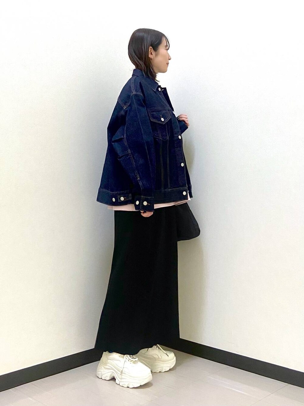 ブラック系のスカート、ブラック系のトートバッグ、ホワイト系のスニーカーを着用したレディースの冬コーディネートの4枚目の写真