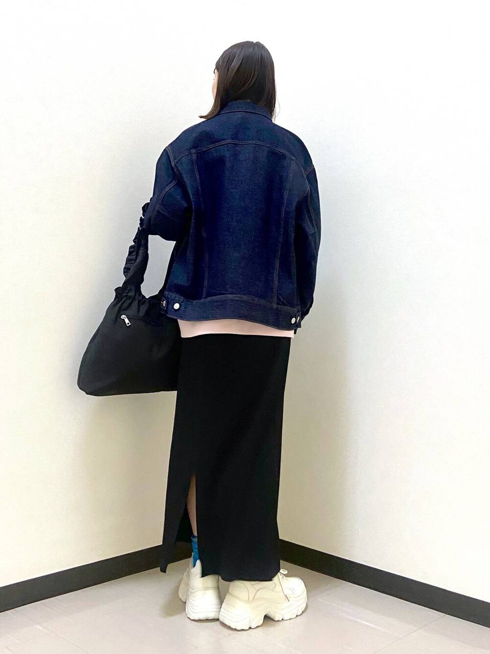 ブラック系のスカート、ブラック系のトートバッグ、ホワイト系のスニーカーを着用したレディースの冬コーディネートの3枚目の写真