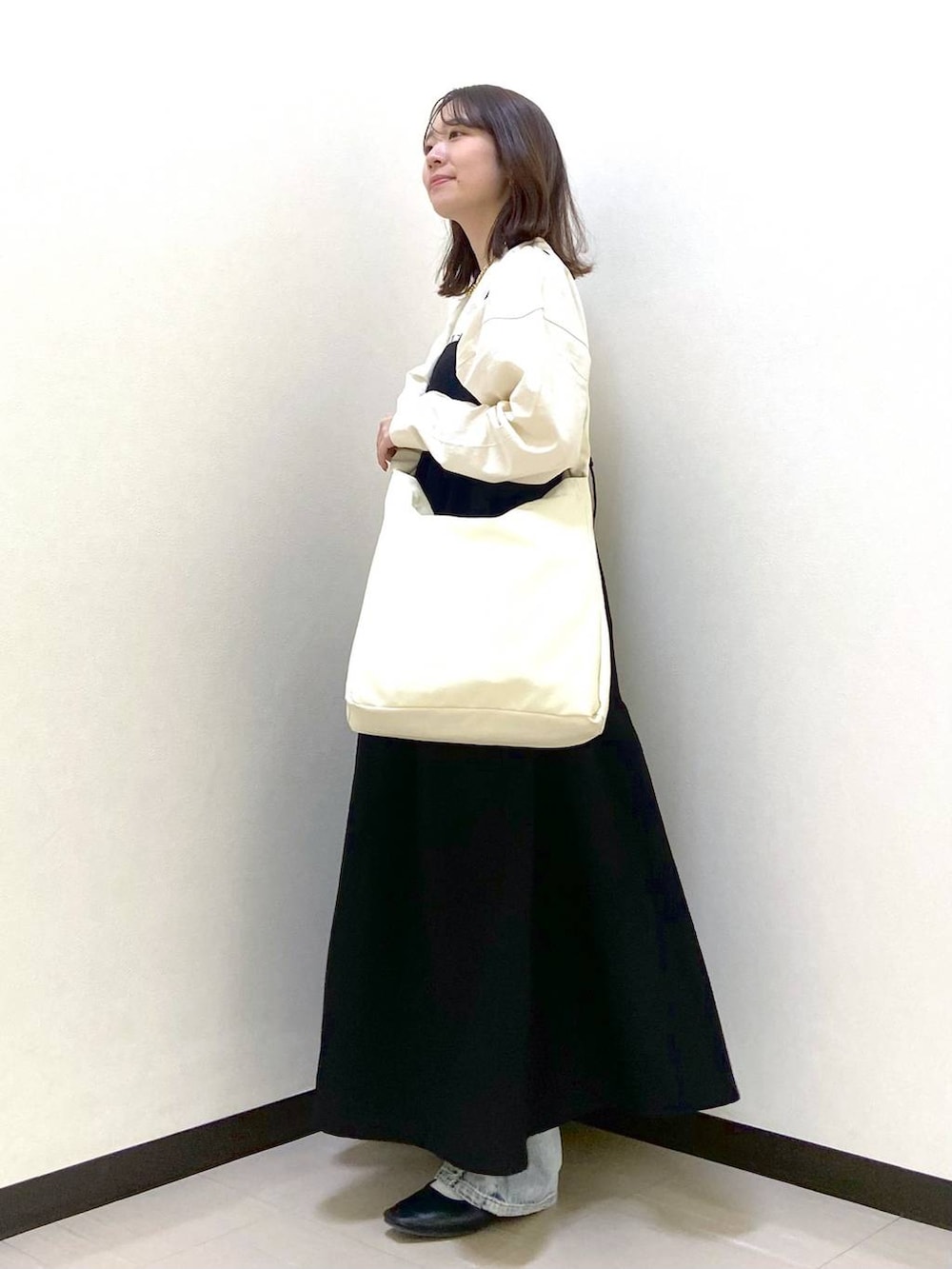 ベージュ系のトートバッグ、ブラック系のパンプス、ブルー系のデニムパンツを着用したレディースの春コーディネートの3枚目の写真