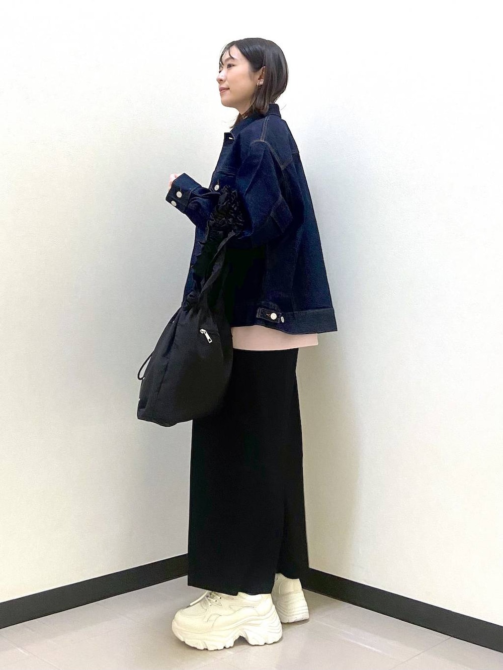 ブラック系のスカート、ブラック系のトートバッグ、ホワイト系のスニーカーを着用したレディースの冬コーディネートの2枚目の写真