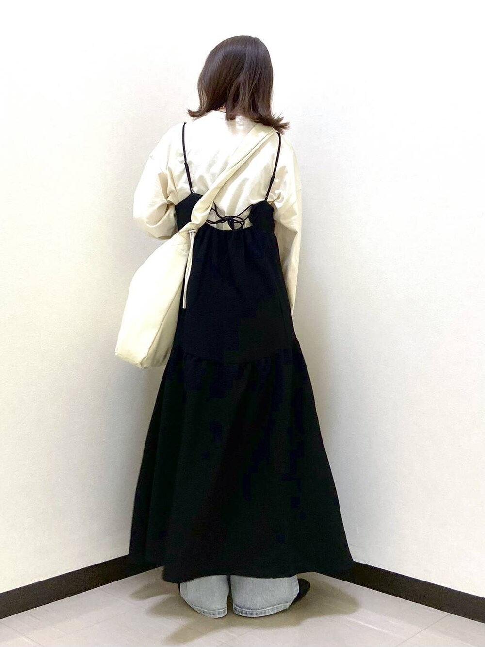 ベージュ系のトートバッグ、ブラック系のパンプス、ブルー系のデニムパンツを着用したレディースの春コーディネートの4枚目の写真