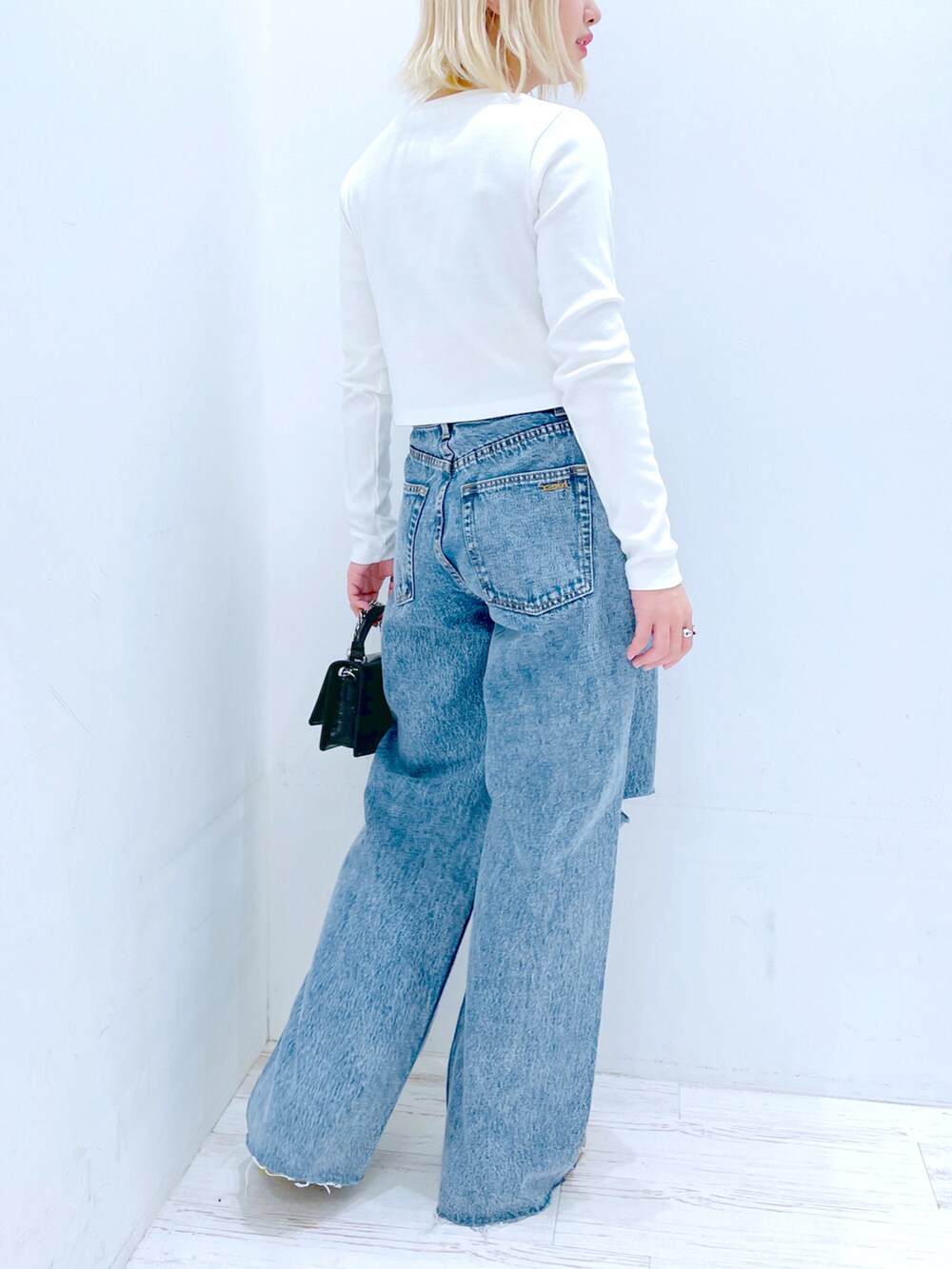 ホワイト系のTシャツ/カットソー、ブルー系のデニムパンツ、ブラック系のショルダーバッグを着用したレディースの春コーディネートの2枚目の写真