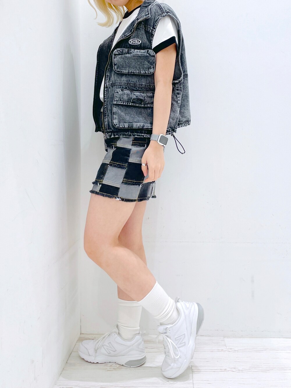 ブラック系のデニムスカート、ホワイト系のTシャツ/カットソー、ブラック系のベストを着用したレディースの春コーディネートの3枚目の写真