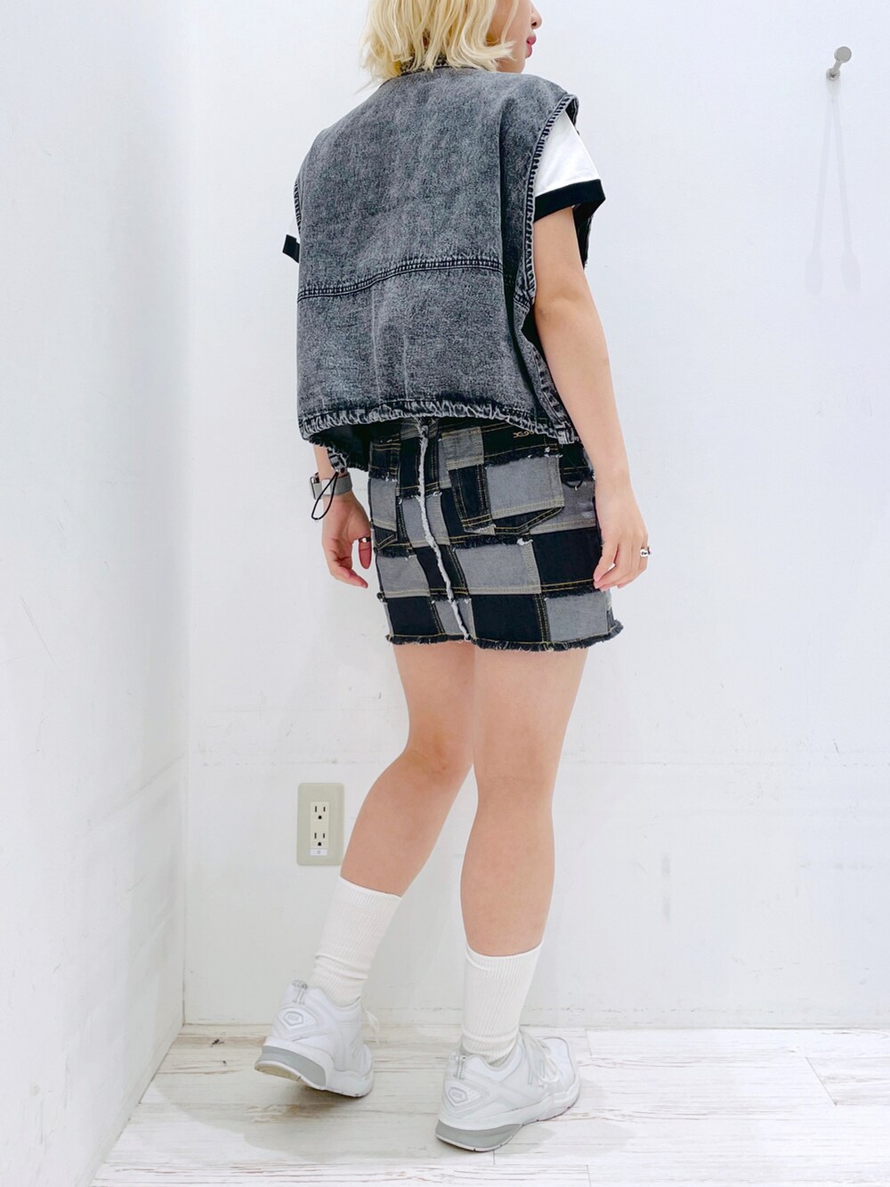 ブラック系のデニムスカート、ホワイト系のTシャツ/カットソー、ブラック系のベストを着用したレディースの春コーディネートの4枚目の写真