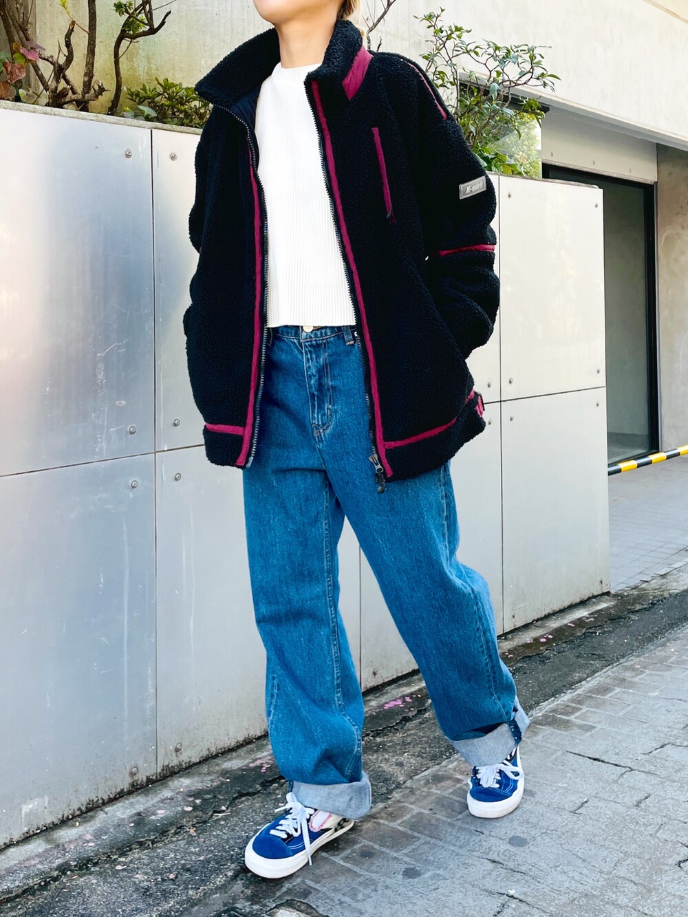 ブルー系のデニムパンツ、ホワイト系のニット/セーター、ブラック系のブルゾンを着用したレディースの秋コーディネートの2枚目の写真